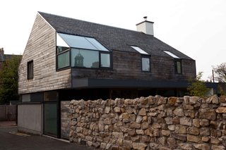 Though the lane on which the Japanese House sits is off the main street, a rock wall affords the small yard quite a bit of privacy. It also nicely frames the second floor of the house from street level. Have a look at the traditional architecture nearby in the reflection in the corner window.
