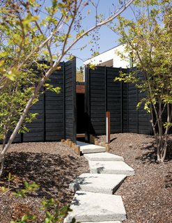 An Atypical Modern Home in Southern California - Photo 2 of 15 - A gently winding set of exposed aggregate concrete pads leads to the Wabi House’s front door. Mariscal sought to "hide the house behind a dense forest front yard." As the crape myrtles grow in, they will further filter the home’s facade.