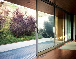 An Atypical Modern Home in Southern California - Photo 10 of 15 - A custom-tailored mechanism allows six floor-to-ceiling sliding glass doors to open along the entire width of the living space, creating a seamless transition from indoors to out.