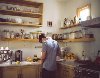Josh Nissenboim prepares food in the kitchen. The countertop is Carrera marble, chosen because for its lightness and ability to wear in naturally.