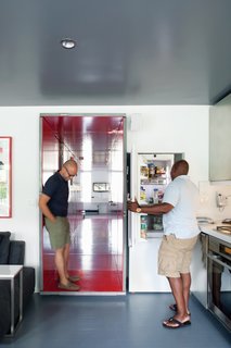 Moving the kitchen out of the hallway and rotating the front door 90 degrees and into the tunnel created a much-needed foyer. "Before, when someone entered, they walked straight into the living room," Russell says. "The lighting from the staircase would ruin the buzz of the party inside." <br><br>The new entrance opens into the narrower of the two corridors, from which individuals can access the storage-and-laundry closet, shower room, and powder room. In the kitchen, a 9.4-cubic-foot, 24-inch Liebherr fridge and freezer is tucked into the wall. "I freaked out when I saw it for the first time because it was so tiny," Russell says. "But it hasn’t been an issue at all; it was just a mental thing. We’ve learned how oversized our old fridge was."