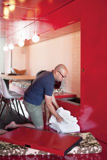 The reused doors serve as more than floor, walls, and ceiling; several are still functional. In the dining room, the benches lift up for storage, and doors on either side of the banquette open to reveal closets.