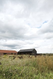 A Pair of English Barns Hide Unabashedly Bold and Budget-Friendly Minimalist Interiors - Photo 1 of 14 - Tucked away in a corner of Norfolk County, England, this pair of barns—one new, one renovated—sit low in the vast countryside.