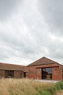 A Pair of English Barns Hide Unabashedly Bold and Budget-Friendly Minimalist Interiors - Photo 3 of 14 - The large windows are set back behind the brick facade allowing the residents to get an additional glimpse of the depth and detail of the original bricks.