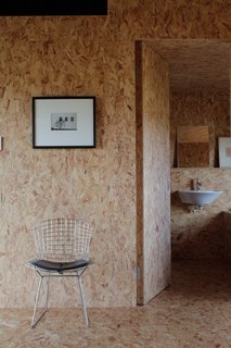 A Pair of English Barns Hide Unabashedly Bold and Budget-Friendly Minimalist Interiors - Photo 6 of 14 - A wire side chair by Harry Bertoia for Knoll sits outside the bathroom in the Stealth Barn.
