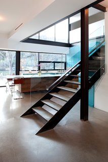 The kitchen is a double-height space at the core of the house, with views to the lake beyond. A long horizontal opening in the wall above the lacquered turquoise cabinets allows for views from the kids' play area. Photo by Brian Mihealsick.