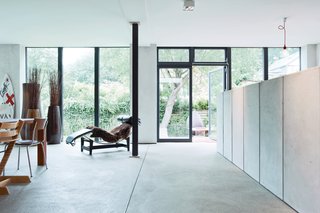 An LC4 lounge by Le Corbusier for Cassina keeps company with a trio of large planters and a surfboard in the space between the kitchen and the dining room.