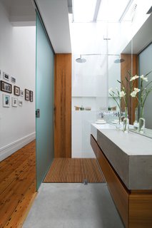 Bathed in Light<br><br>To help disperse light in the newly opened-up interior, the designers clad the roof over the guest bathroom with Danpalon, a translucent polycarbonate that brings in lots of softened natural light. The walls and door are frosted glass. Says Kyprianou: "You can’t see much through the glass—just silhouettes—so our guests don’t mind!" danpalon.com.au<br><br>Hung Up<br><br>With the budget running out toward the end of the project, Kyprianou wanted to avoid forking out for a custom-designed walk-in closet in the master bedroom. So he conceived of a simple and cheap storage solution: drilling holes through the wooden roof trusses and feeding inexpensive aluminum closet rods through. junolightinggroup.com