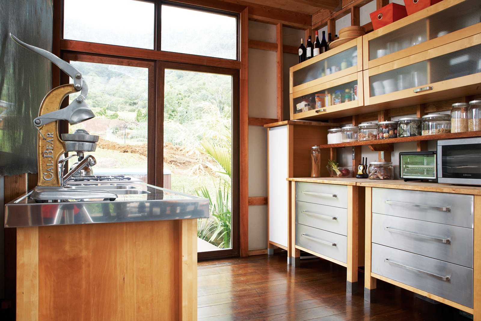 The kitchen occupies one corner of the L-shaped structure. As throughout, the floors are made up of reclaimed eucalyptus that Chris planed himself.