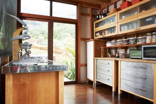 The kitchen occupies one corner of the L-shaped structure. As throughout, the floors are made up of reclaimed eucalyptus that Chris planed himself.
