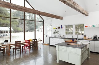 The table is situated in front of the house’s rear wall of skyscraper glass. Laminate kitchen cabinets by Ikea are framed in wraparound bluestone; the 48-inch commercial range is by FiveStar.