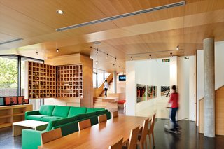 In the open-plan kitchen, dining, and living area, the family cohabitates comfortably with their art. The wooden furniture was custom built for the space by the Melbourne designers Xilo.