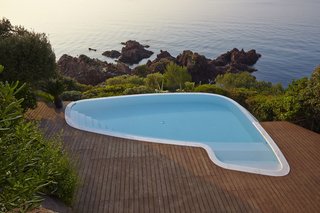 The swimming pool was reshaped and refinished to blur the transition between deck and rocky outcrop. Beyond the pool is the villa’s private beach, framed by lush vegetation.