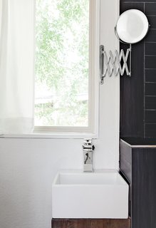 In the bathroom, a chrome waterfall faucet by LightInTheBox tops a 12.6-inch-square Mini Nova basin by Barclay; a retractable Ikea mirror is the only concession to vanity.