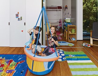 This House Doesn't Hold Back on Colorful Details - Photo 3 of 11 - In their bedroom, Anya and Yash hang out in the boat-shaped swing by Haba that their aunt brought them from Germany (it’s not currently available in the United States). A Rapson Rapid Rocker by Rapson-Inc. sits next to the window.