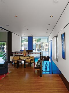 This House Doesn't Hold Back on Colorful Details - Photo 7 of 11 - In the living room, a vintage table and chairs by Edward Wormley sit in front of a Florence Knoll wall unit with a vintage jewelry chest by George Nelson for Herman Miller. The Hinaki pendant light over the stairs is by David Trubridge.