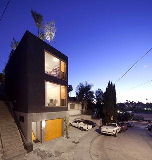 30 All-Black Exterior Modern Homes - Photo 21 of 30 - Storey calls this house the "Eel’s Nest," after the narrow urban properties that go by that name in Japan. Its façade was originally going to be wood, but because of local building codes and the fact the building is built along the edge of the property line, the exterior had to be fireproof. Storey covered it with stucco instead. "I wanted it to look as rough as possible," says the architect. "Since it’s such a small house, it needed to be tough-looking."<br><br>The workshop at ground level measures less than 200 square feet, but is set up to accommodate any kind of woodworking or welding; when not in use, the architect parks his car inside.