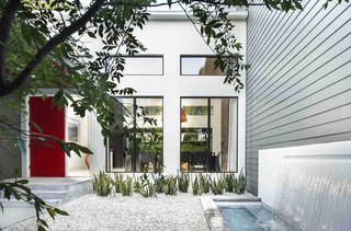 The red door was De Azevedo's idea, says Phil Kean, president of the Phil Kean Design Group. It adds a spash of color to the front courtyard, which is simply landscaped with gravel and low-maintenance plants. A water feature was installed next to the James Hardie fiber-cement siding.