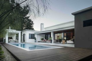 Accordion-style glass doors open the living room up to a lanai, or covered veranda, that in turn opens via a pair of retractable screens onto a pool deck. The effect is to create a single seamless space that merges the living room with the outdoors.