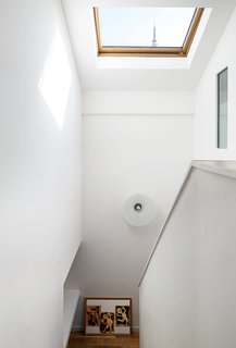 The antenna of Claude Vasconi’s TDF television tower is visible through the Velux skylight architects Caroline Djuric and Mirco Tardio added to a family house in France. "It’s very French, very angular," Djuric says of the renovation. The light fixture was found at a brocante, or vintage market.