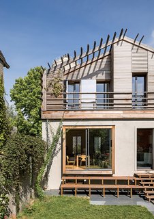 The back of the house was designed as a contemporary counterpoint to the more traditional front facade. The sliding doors and windows are by Technal. An asymmetrical wooden stairway leads down to the garden.