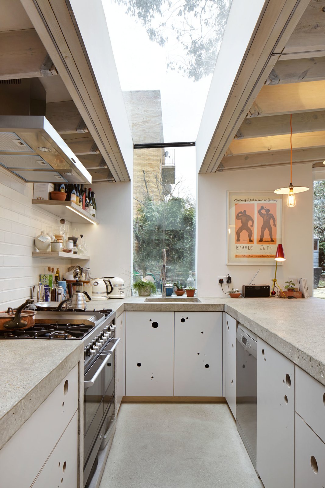 A sturdy concrete countertop curves around the entire length of the kitchen, finished in a texture Webster describes as “bug splattered.” Despite the unappetizing name, it works well for rolling out dough. Its circular motif reappears in the custom cabinets’ finger pulls, which also help ventilate the cupboards. The fixtures are from Kubus and the appliances are from Miele.