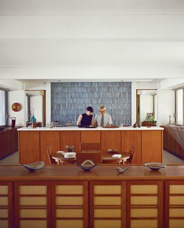 Stacey and Doug prepare food before the kitchen's massive wall of soothing tile from Heath Ceramics.
