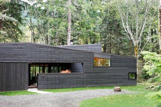 30 All-Black Exterior Modern Homes - Photo 1 of 30 - "From the street, it appears as a rectangular building with sloping shed roofs, but this is actually an illusion," Hutchison notes. "The floor plan is actually U-shaped, wrapping around an entry courtyard that is contained by the continuous west facade." A standing seam metal roof by Custom Bilt Metals blends in with the cedar siding.