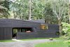 “From the street, it appears as a rectangular building with sloping shed roofs, but this is actually an illusion,” Hutchison notes. “The floor plan is actually U-shaped, wrapping around an entry courtyard that is contained by the continuous west facade.” A standing seam metal roof by Custom Bilt Metals blends in with the cedar siding. Photo 2 of Courtyard House on a River modern home