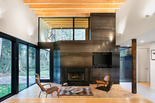 “From the courtyard, you then enter the house proper, directly into the main living room,” Hutchison says. “From this room, you have a panoramic view looking out through the trees to the river, or back into the courtyard.” The wood-burning fireplace, from Majestic, is clad in steel panels. Eames Molded Plywood lounge chairs sit side-by-side in the living room. Photo 4 of Courtyard House on a River modern home
