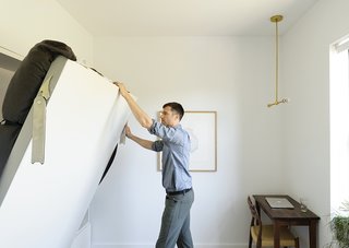 How One Family of Three Does It All in 675 Square Feet - Photo 8 of 14 - A Model 78 side chair by Niels Otto Møller tucks into a custom desk in the master bedroom, a home base from which Friedlander works remotely. The brass pendant light is by Allied Maker.