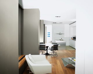 The openness of the space is underscored by largely neutral furnishings. The window wall is surrounded by a Benjamin Moore hue that matches the dark, bronze-colored aluminum frames. In the restrained Bulthaup kitchen, a large-scale photograph of a jet by Jeffrey Millstein is a major focal point. The Saarinen table is from Knoll; the Eames chairs are from Herman Miller.