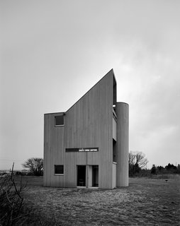 Modernist Angular Residence with Vertical Cedar Siding - Photo 3 of 6 - The private guest quarters are nestled on the ground floor, while the public spaces (open-plan living-dining room and kitchen on the second level; studio and master bedroom on the top) are elevated to capitalize on views out past the dunes to the Atlantic Ocean.