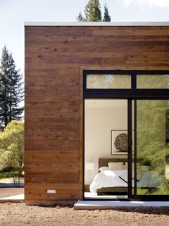 This Couple Achieves Their Glass House Goals - Photo 4 of 5 - The modestly scaled master bedroom opens to a view of the woods located behind the property.