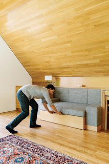 A couch—upholstered by local firm Revive Upholstery & Design—slides out on hidden casters and transforms into a full-size bed (with the headboard doubling as a linen cupboard) where guests can sleep.