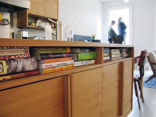 8 Ways to Organize Your Books with Storage Cubbies - Photo 5 of 8 - Cubby holes under the kitchen counter house cookbooks. The cabinets are made from salvaged wood. "The kitchen is where they like to be at home," Bischoff says. "That's why it's in the middle of the floor plan."