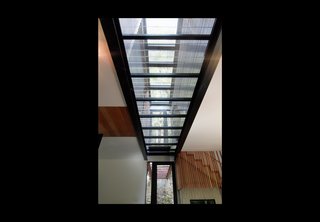 A close-up shot of the glass "spine." Fenster placed the units four feet apart from each other to allow light into the home. The grated bridge continues through the home to the outside path, integrating the structure with its landscape.