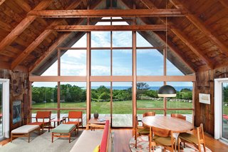 Jens Risom's Block Island Family Retreat - Photo 2 of 13 - In the living and dining area, where mostly vintage Risom furnishings share space with a few new additions, the view facing north is framed by the wall of glass.