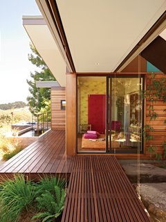 A slatted walkway leads into the new library, which the Gimons have outfitted with a Topissimo rug by Nani Marquina, Grove Garden wallpaper from Osborne & Little’s Tara collection, and a pink Chroma Sassy sliding wall panel by 3form.