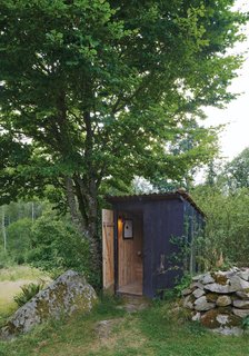 The family's main bathroom—a rustic wooden outhouse—is illuminated by Arne Jacobsen's iconic AJ wall lamp.