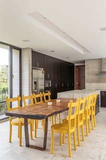 25 Bold Ways to Decorate with Yellow - Photo 23 of 25 - The custom kitchen counters are concrete, and the yellow dining chairs add a welcome splash of color.