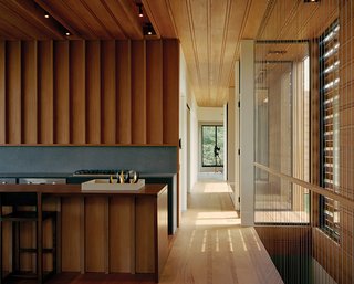 The adjacent open kitchen is made of mahogany (to match the floors, ceilings, and walls), accented by a volcanic stone backsplash and a Viking gas cooktop.