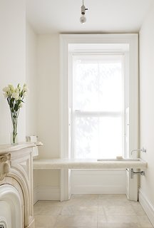 Architects Anne Marie Lubrano and Lea Ciavarra limited the material selection in their renovation of a town house dating from 1899. The powder room on the first floor is located in a former waiting area (the previous resident used the level for his dental practice). It features a custom Alabastro marble sink and fixtures by California Faucets. The architects kept the original fireplace, paying homage to the structure’s history. Benjamin Moore’s Super White paint was applied to the ceiling and the White Dove hue to the walls. "Positioning the faucets on the side wall emphasizes the horizontal," Lubrano says. "Wall-mounted fixtures feel less grounded and materials can continue uninterrupted below. We wanted the spaces to feel light, spacious and light-filled."