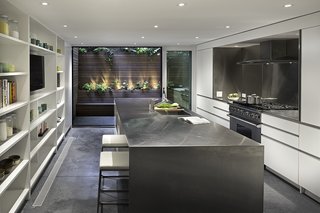 Inspired by the client’s affinity for Donald Judd’s metal boxes and her request for a surface that could handle heavy use and abuse, Lubrano and Ciavarra wrapped the kitchen island, the counters, and the backsplash behind the Viking range and Miele hood in brushed stainless steel. The integrated shelving accommodates the resident’s expansive cookbook and tableware collection. The kitchen’s HVAC system is located in the cellar and blows through vents set into the concrete floor.