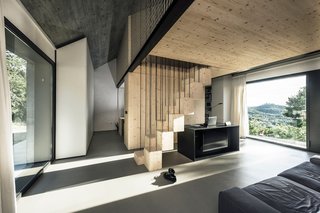 The kitchen, living area, and bathroom are located on the ground floor. Large windows overlook the surrounding forest, and Italy to the west.