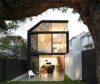 The addition’s two stories of cedar-framed sliding doors and window provide generous views of the house’s prized jacaranda tree. The addition’s polished concrete floor and white cladding extend into the garden, drawing occupants to the serene rear porch. There, they can relax on stools designed by Alvar Aalto and Charles Wilson while admiring the luscious greenery.