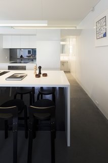 Renovation Near Sydney Opens Home Onto a Lush Garden - Photo 4 of 8 - Casual meals are eaten at the kitchen’s glacier white Corian countertop, which features Aalto K65 stools. The island’s Blanco sinks offer a direct, uninterrupted sightline to the garden.