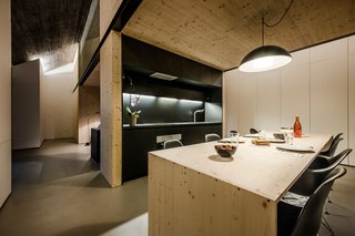 The kitchen uses laminated chipboard for the countertop and cabinets, and the same plywood used throughout the house for the table. The lamp is IKEA.