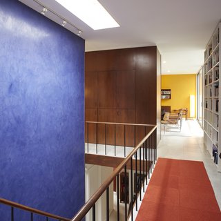 The interiors of Hugh Smallen's 1963 Becker House are accented by a rich blue that connects the two levels, while a vibrant yellow draws attention towards the living room.