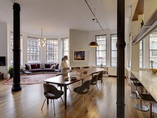 This living room opens to the dining room, which abuts the kitchen and home office. The walnut dining table, pictured here with an extension leaf in place, was designed by BSC. "The family needed a table that extends for large family dinners, but didn’t feel too formal for everyday use," Stageberg explains, adding, "Most meals happen around the broader end, but the table can expand to seat up to fourteen." The dining chairs are Saarinen and the light fixture above the table is from FLOS.